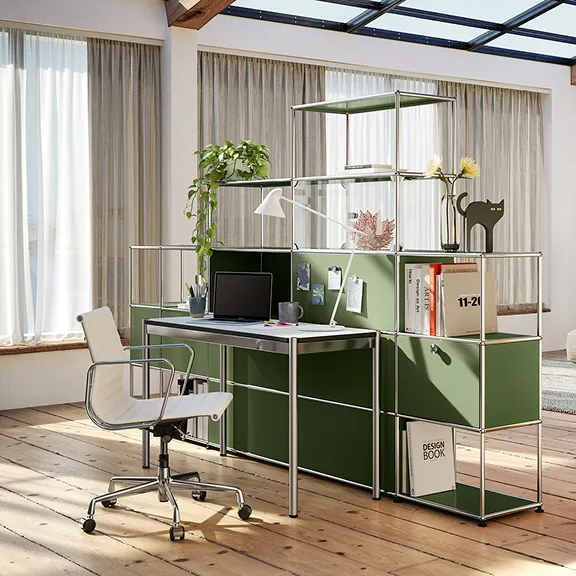 Ein Raumtrenner aus olivgrünem USM Haller, davor ein USM Haller Schreibtisch.
